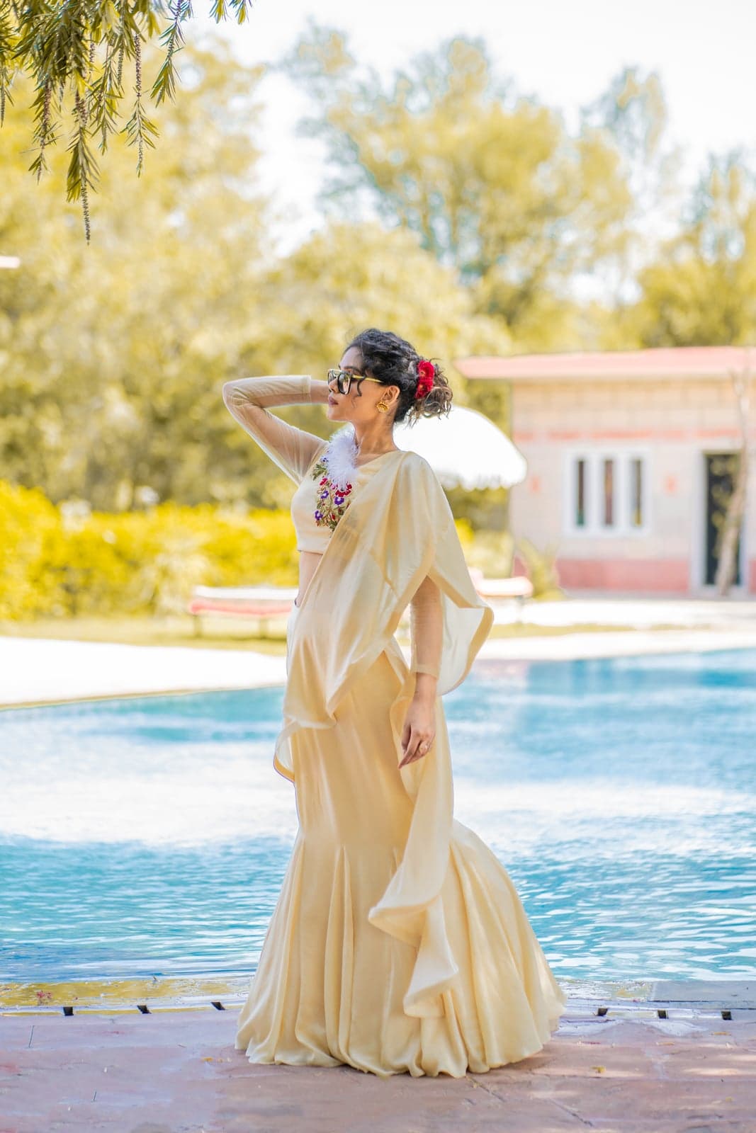Champagne ivory drape gown with a floral-yoke cape and fluted hem — sunlit afternoon by the poolside of a Jaipur villa.