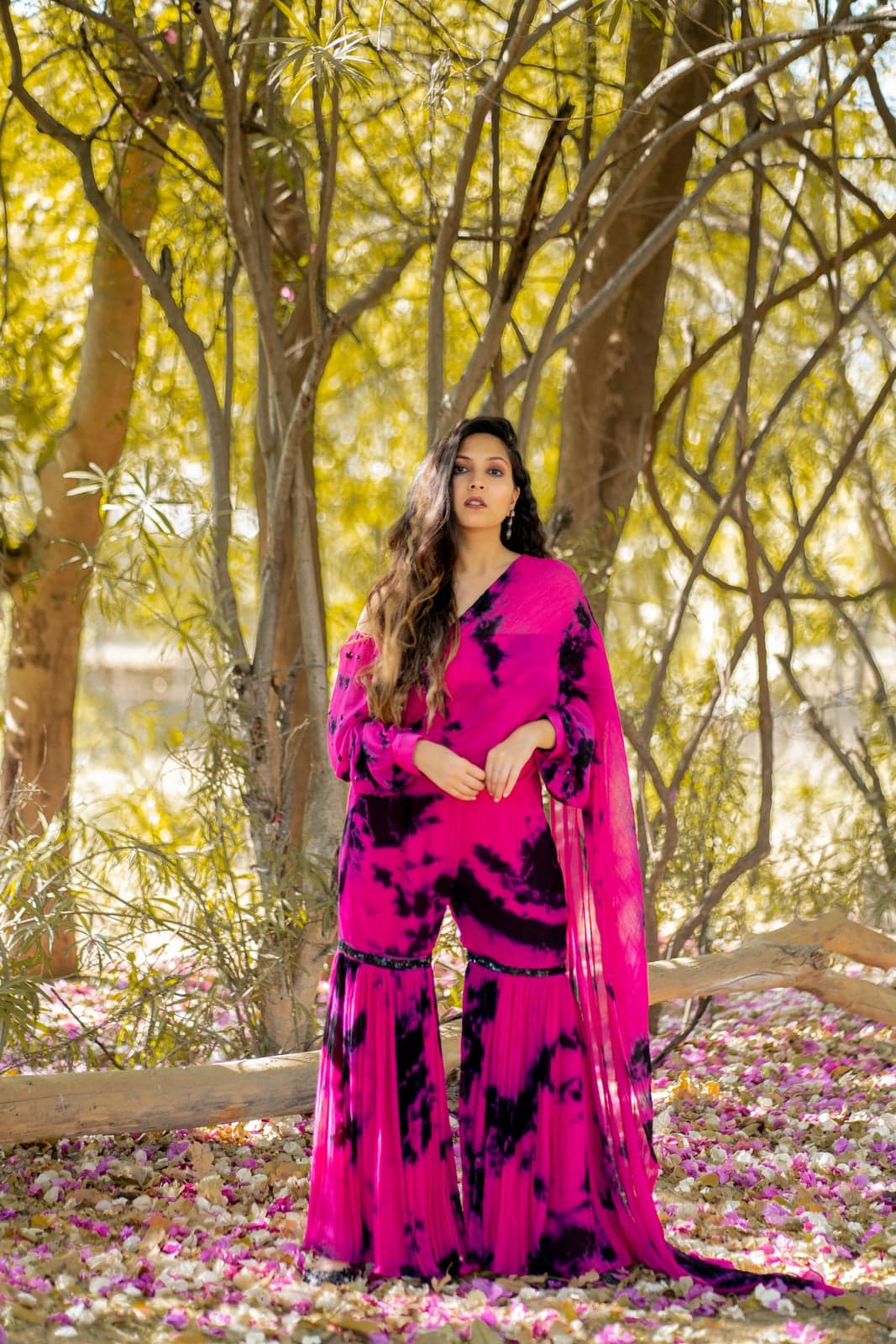 Magenta and black tie-dye gharara — full-length portrait under the marigold-draped mandap canopy.