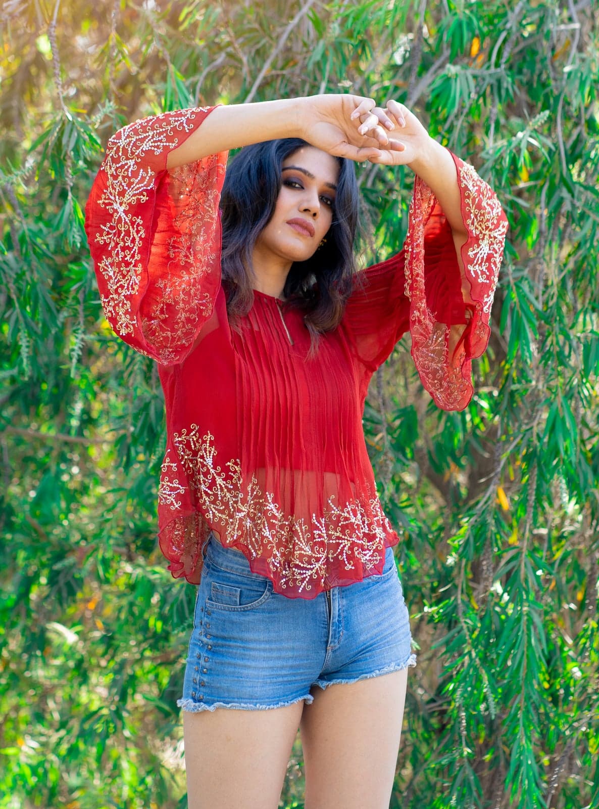 Sheer crimson chiffon top — softer studio-side portrait with embroidered scalloped hem in willow foliage.