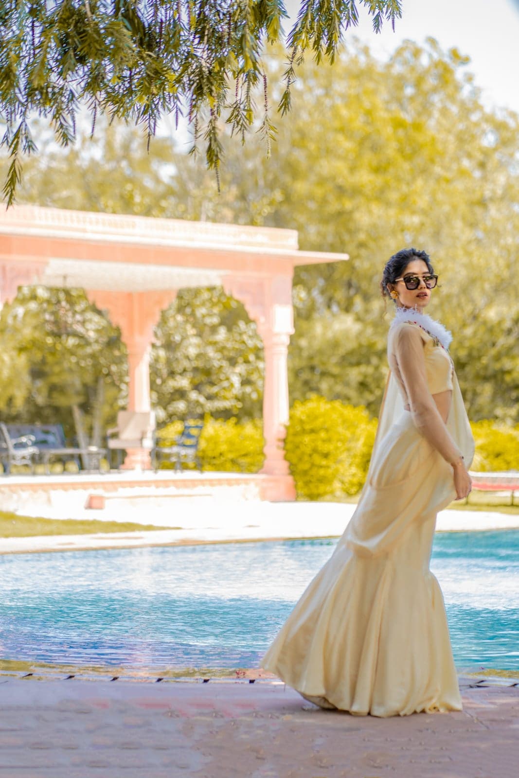 Champagne mermaid lehenga in motion at the poolside — soft afternoon light along the silk train.