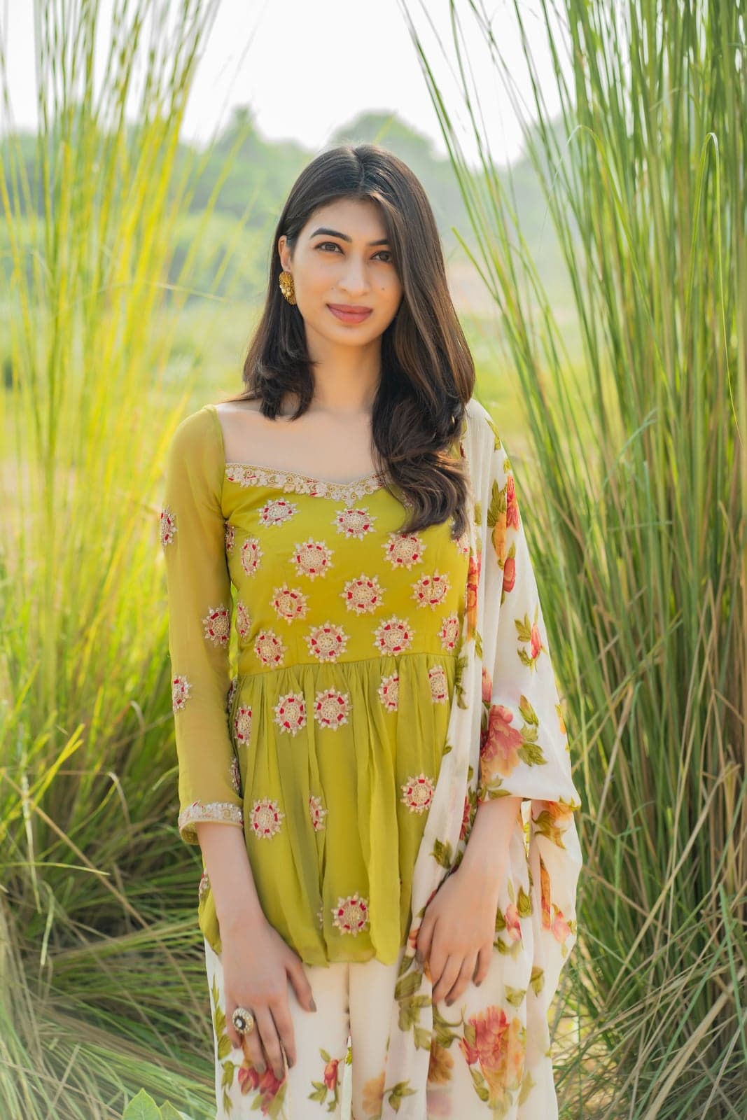 Lime green peplum tunic — closer portrait with the beaded floral motifs and floral-printed dupatta against tall grass.