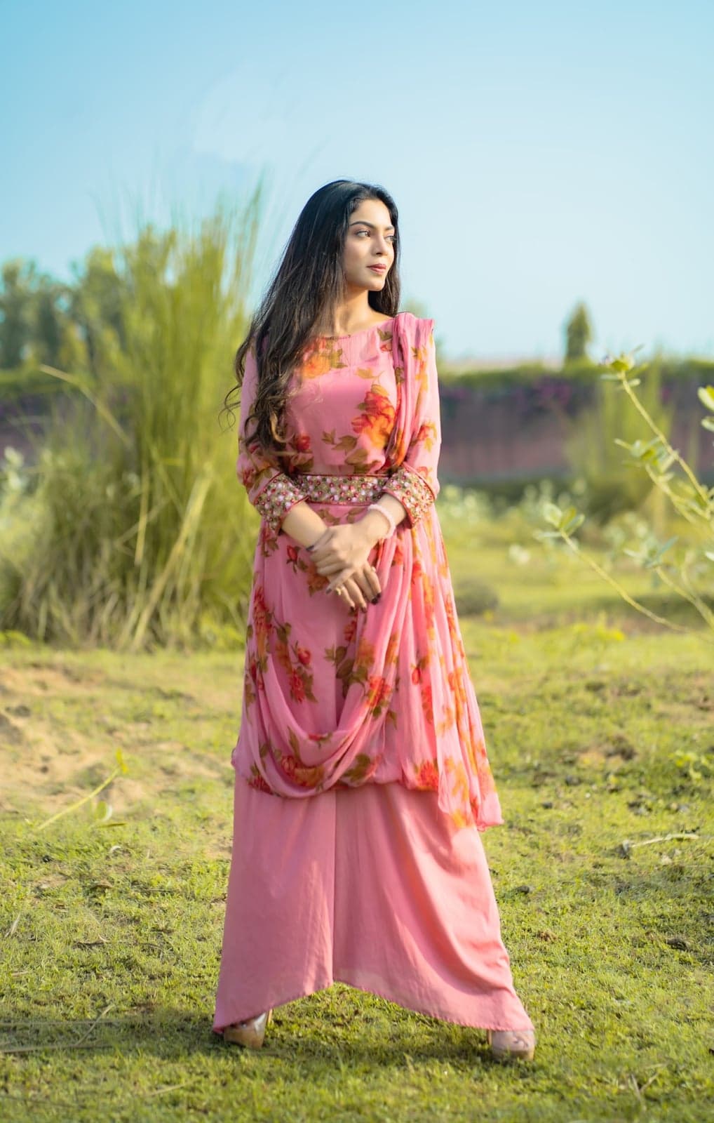 Pink kurta with rose-print sleeves and a draped dupatta — side-on portrait with embellished belt detail.
