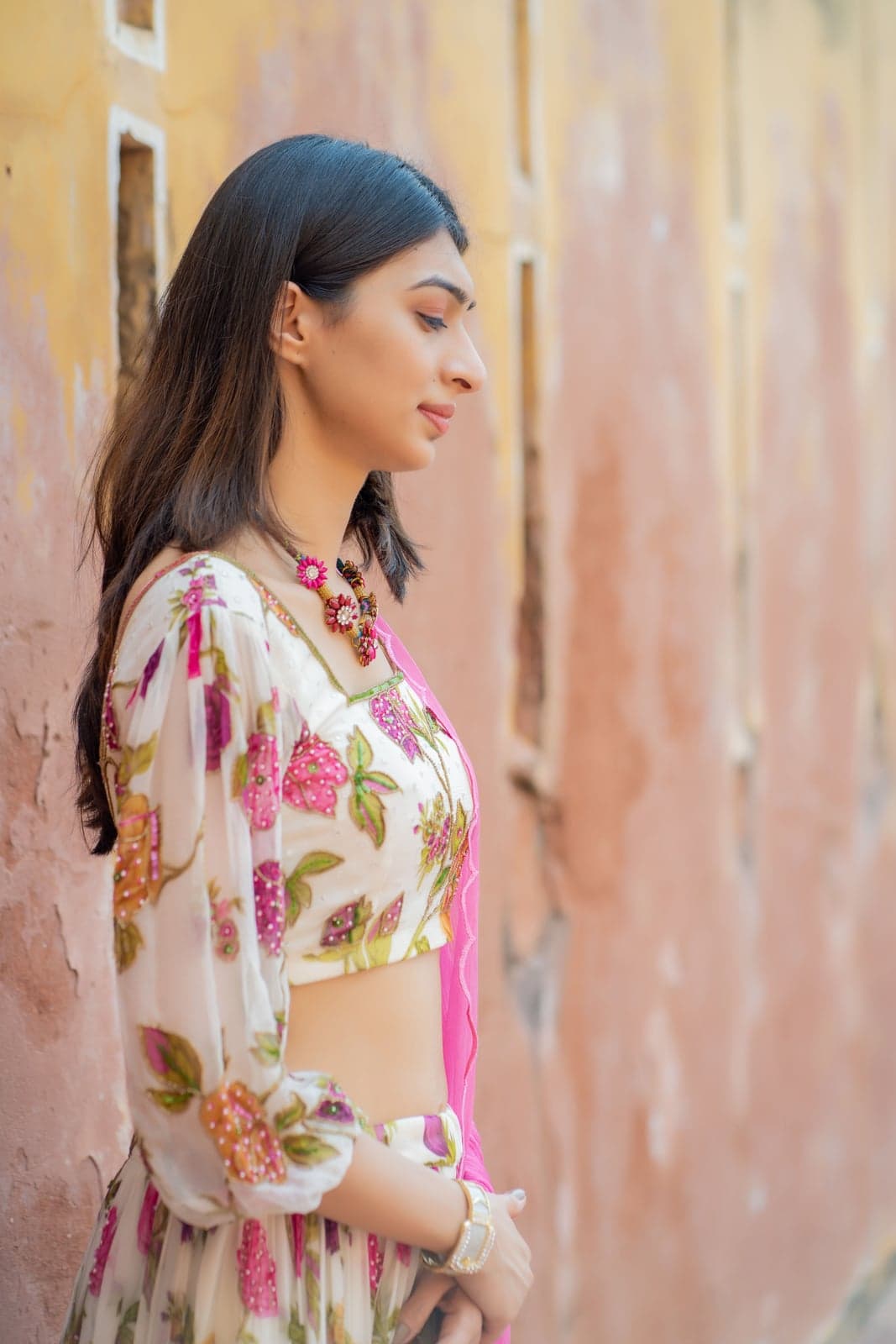 Ivory and pink rose-print maxi — three-quarter outdoor portrait, cinched bodice and floral cascade skirt.