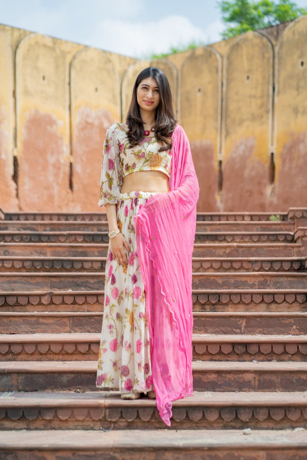 Cream berry-print crop — back portrait with cut-out detail against the ochre fort wall.