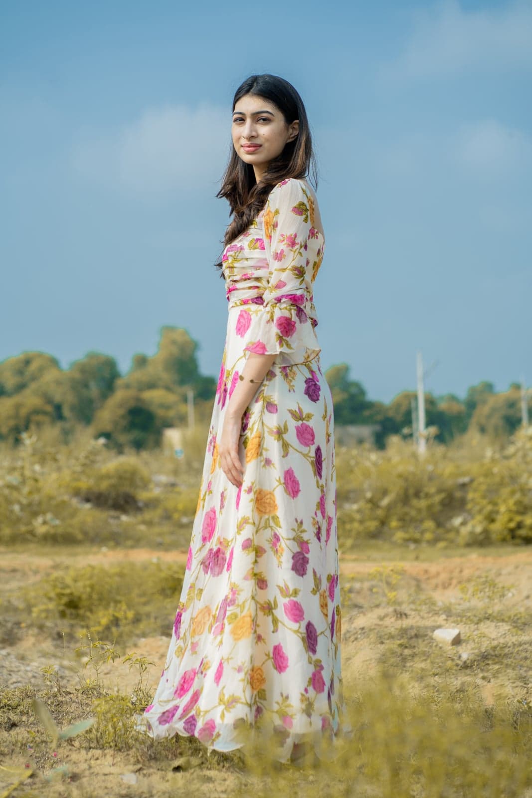 Ivory rose-print maxi — three-quarter side portrait, ruched bodice and tiered skirt in focus.