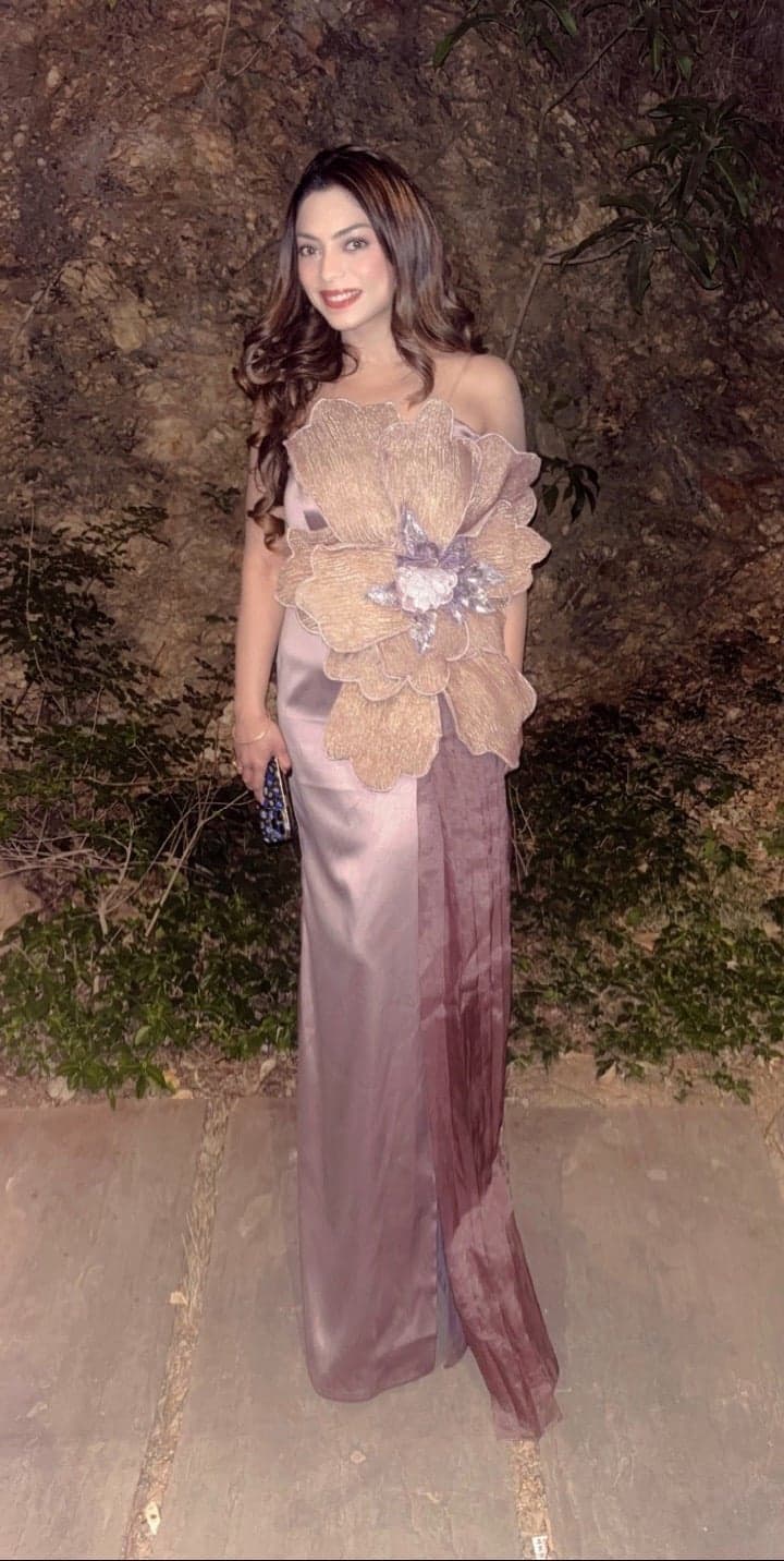 Mauve mermaid gown with a bronze-petal bodice corsage — full-length portrait at a moonlit garden against a rock wall.