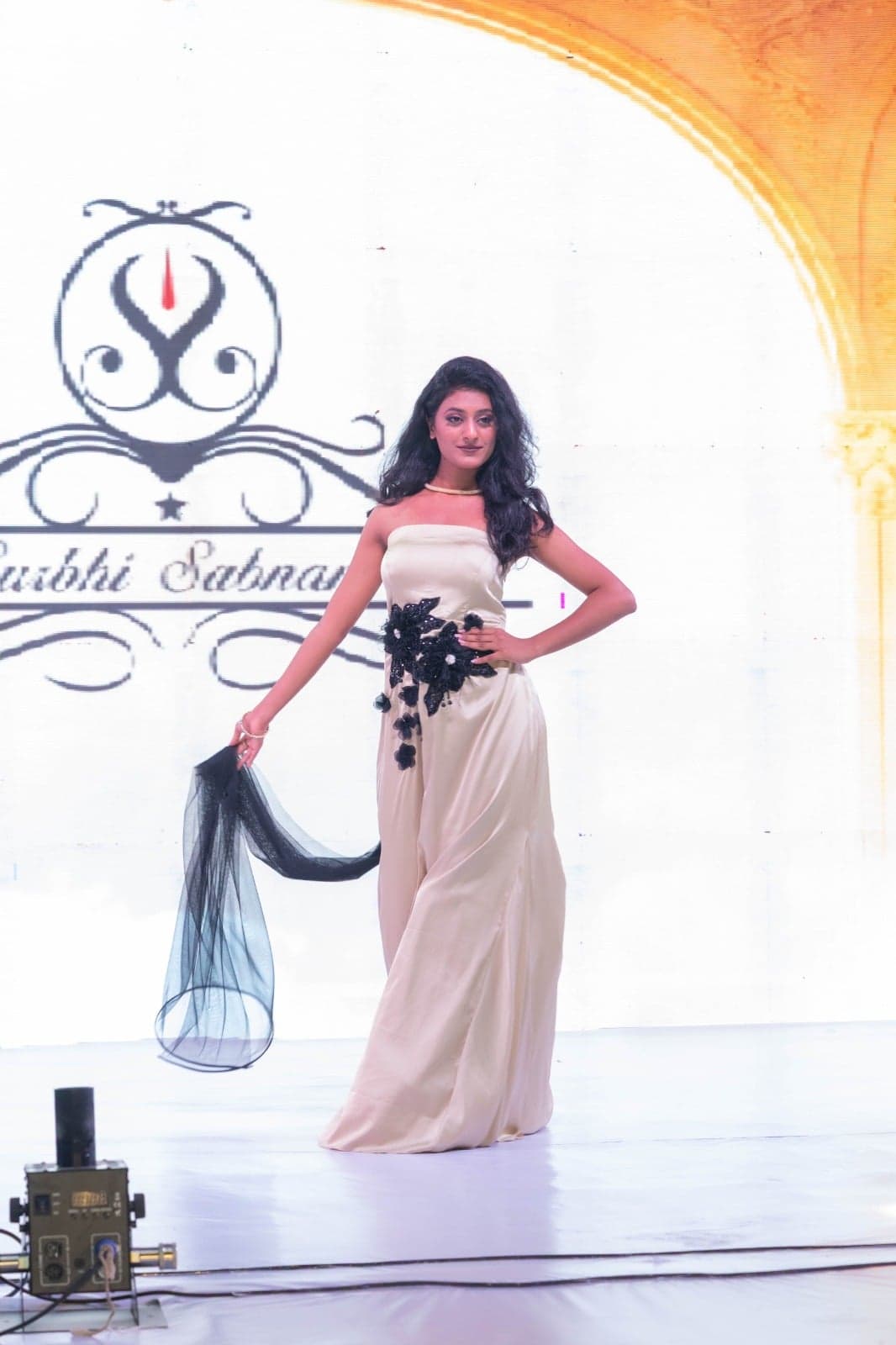 Black strapless feathered-bodice gown with a tiered tulle ruffle hem — side-profile mid-runway.