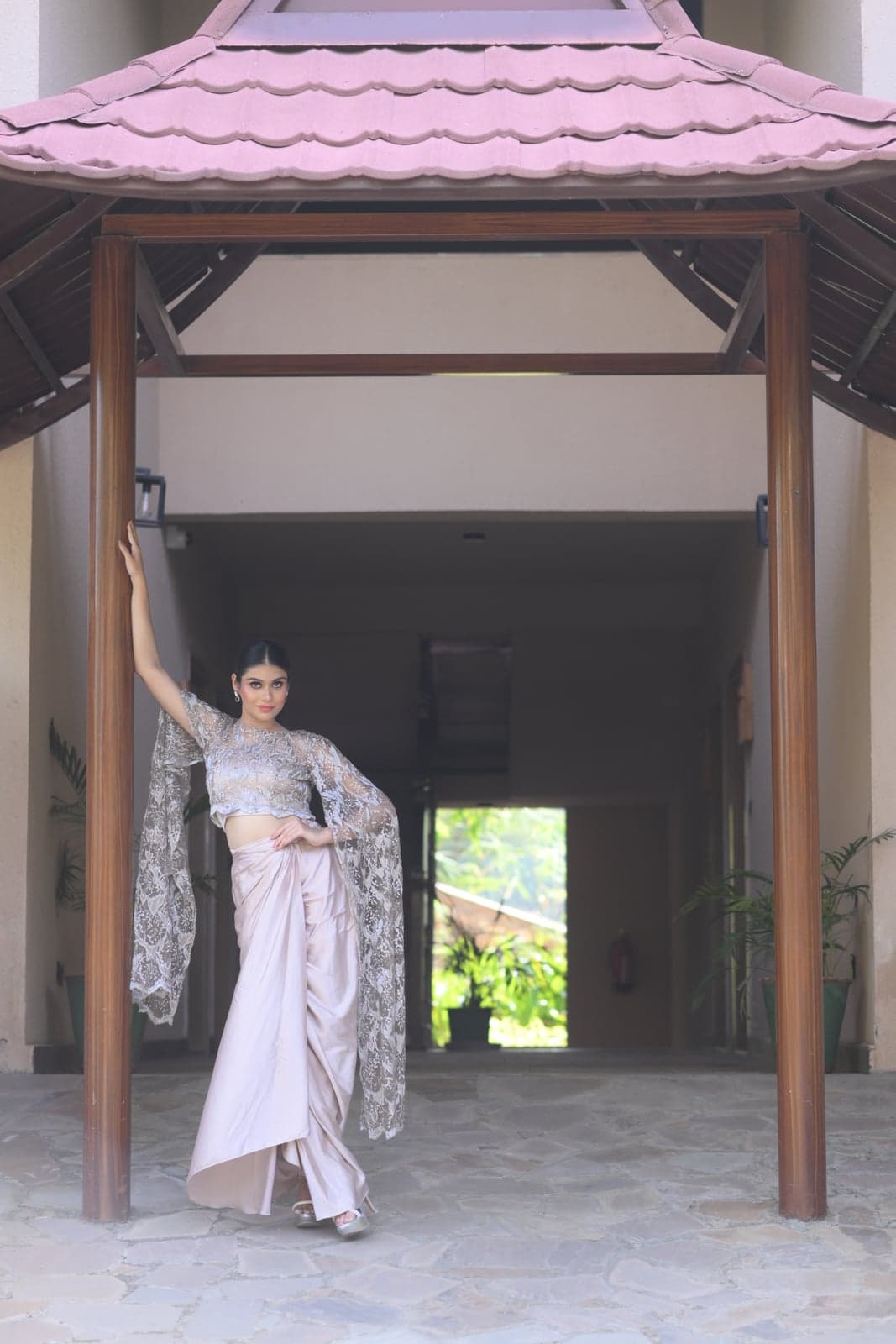 Black velvet saree-gown with feathered bodice — three-quarter view in a sandstone alcove, tulle ruffles tiered down the skirt.