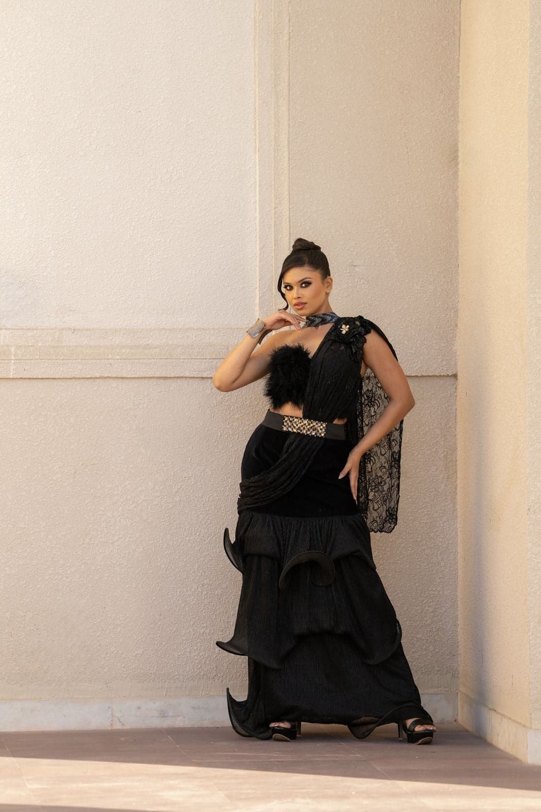 Champagne satin draped gown with a black floral shoulder pin — runway profile beneath stage lights.