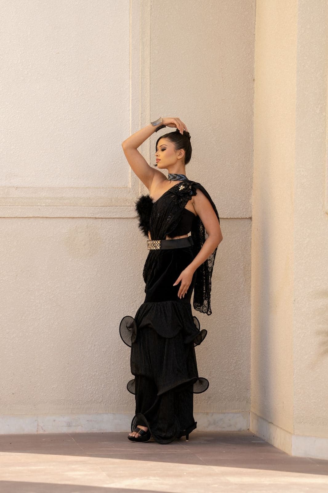 Black sequin mini dress with sleeve-cape — runway walk forward, fluid hem and crystal-chandelier backdrop.