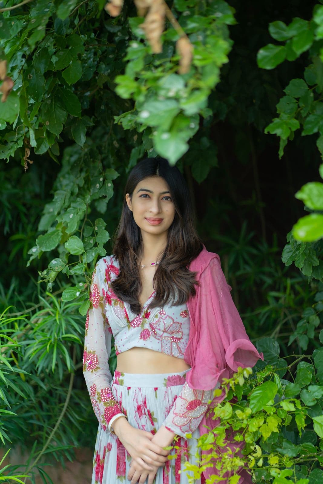 Cream berry-print lehenga and crop set on Jaipur temple steps — pink chiffon dupatta caught in motion above the sandstone tiers.