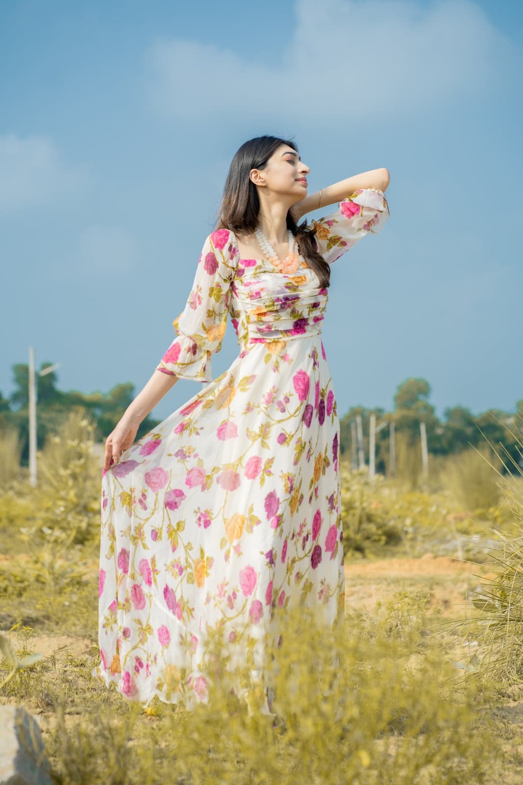 Cream berry-print lehenga set — full-length on the red temple steps with the pink dupatta draped down the side.